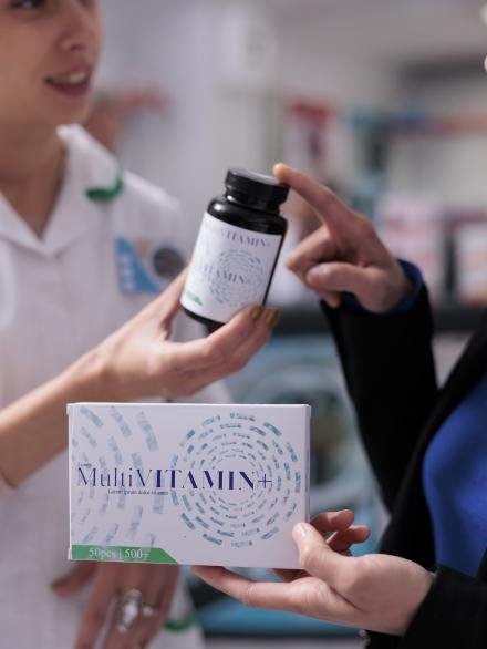 Pharmacist giving cutomer multivitamin bottle in medical retail shop Pharmacist giving cutomer multivitamin bottle in medical retail shop, advising food additive tablets. Drugstore assistant helping client to find dietary supplements prescription